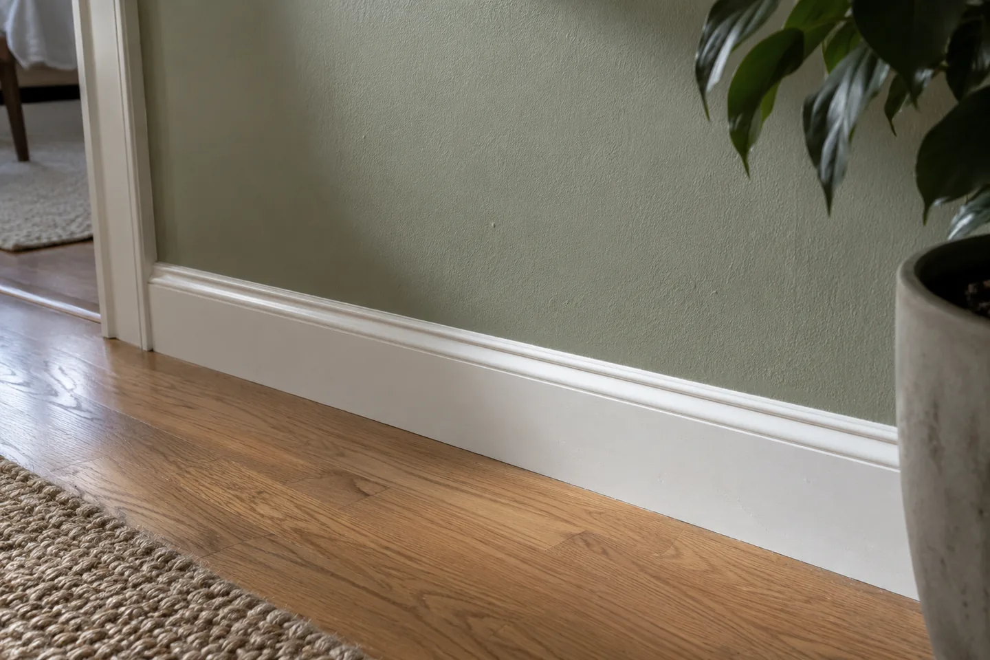 Sage wall and light satin baseboard shown close to an oak floor